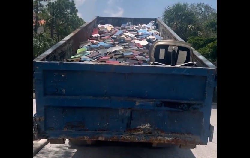 video screenshot of a 20-foot rollaway dumpster nearly full of books (and one office chair) being winched onto a truck video screenshot of a 20-foot rollaway dumpster nearly full of books (and one office chair) being winched onto a truck