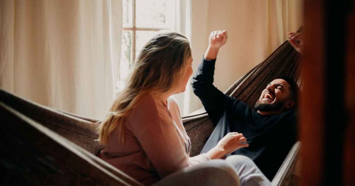 A happy couple enjoying laughter and relaxation in an indoor hammock A happy couple enjoying laughter and relaxation in an indoor hammock