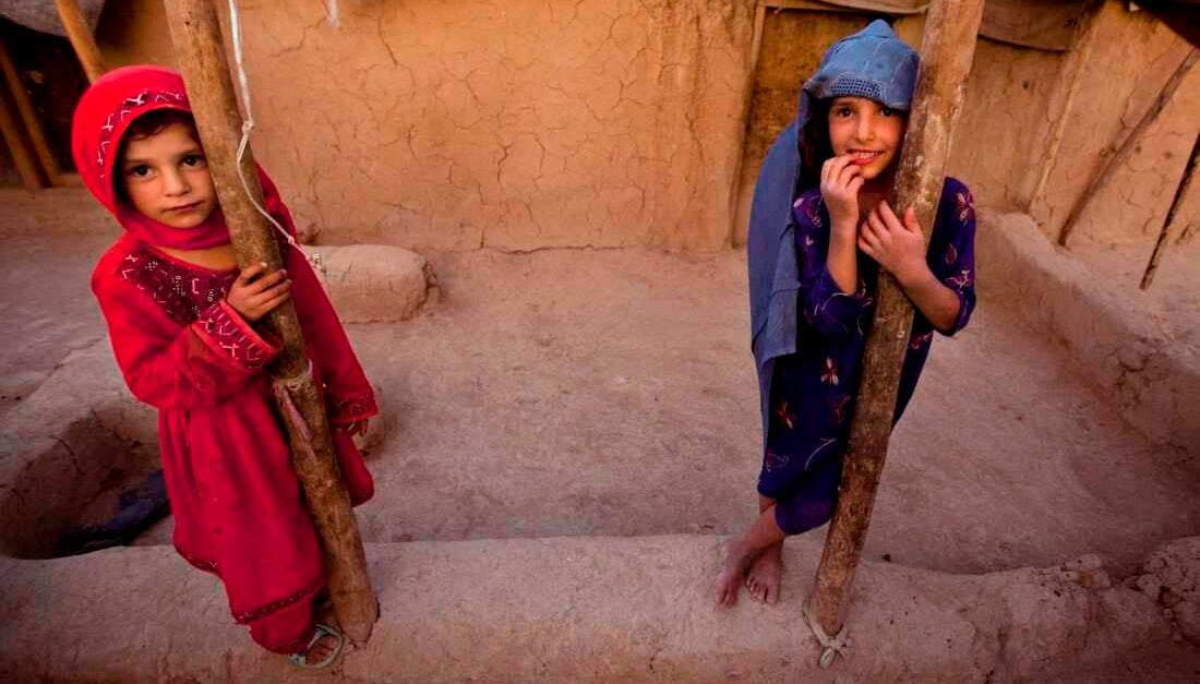 FILE: Zareena, left, and Shakeela, internally displaced Afghan girls play outside a shanty at a refugee camp in the outskirts of Kabul, Afghanistan, Monday, July 25, 2011.