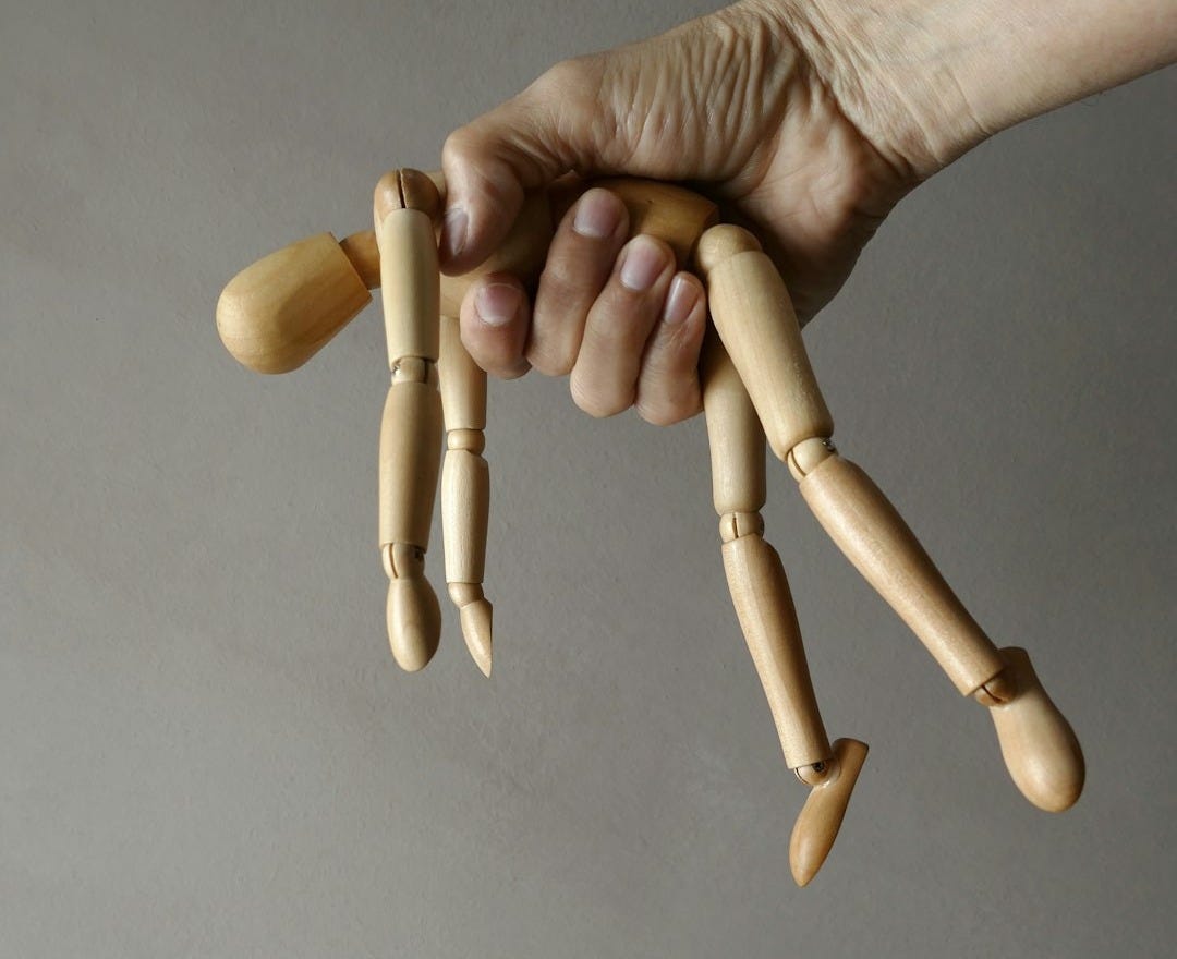 person holding brown wooden mannequin