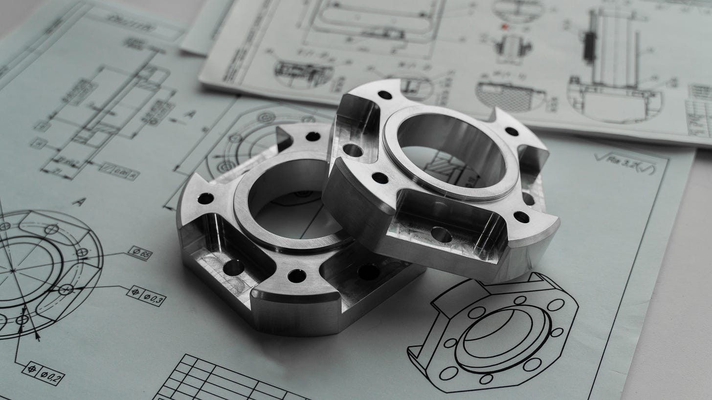 Precision-machined metal components rest on detailed engineering drawings.