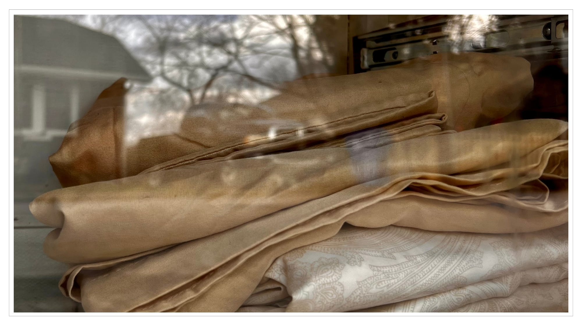 close-up of bed sheets behind glass door