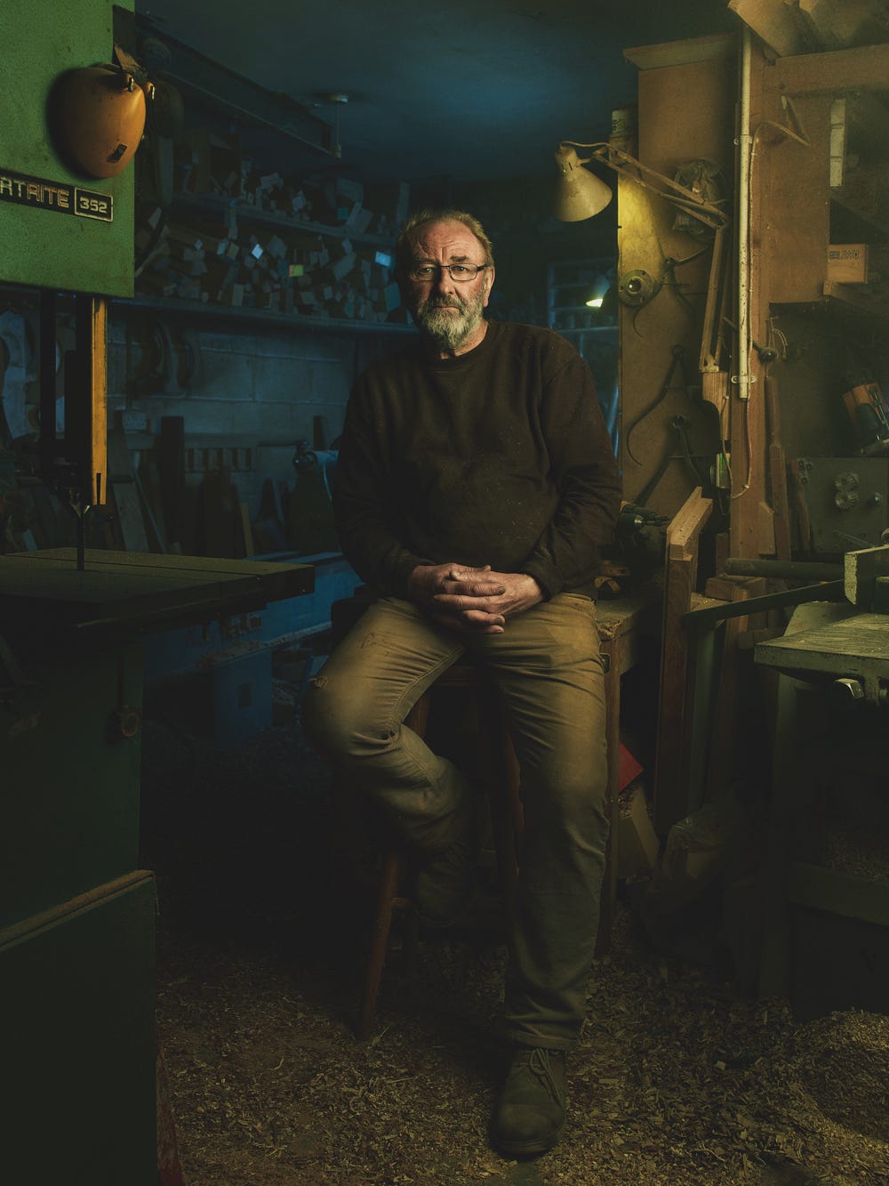 cinematic environmental portrait of an older man in a dark workshop