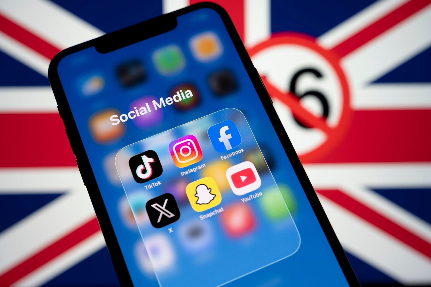 Social media app icons displayed on a smartphone screen in front of a blurred Union Jack flag (Image via Shutterstock.com) Social media app icons displayed on a smartphone screen in front of a blurred Union Jack flag (Image via Shutterstock.com)