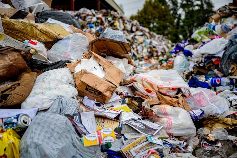 A mound of items send for recycling includes a lot of plastic bags. A mound of items send for recycling includes a lot of plastic bags.