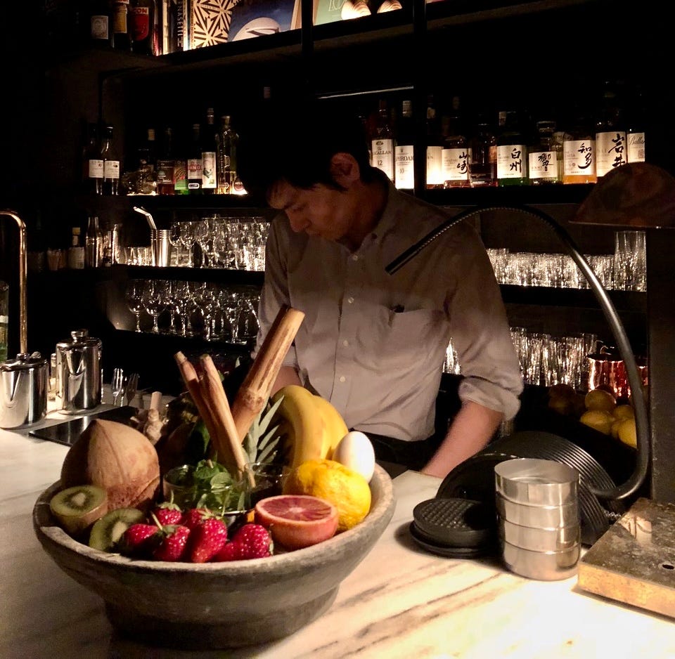 A person making a drink behind a bar.