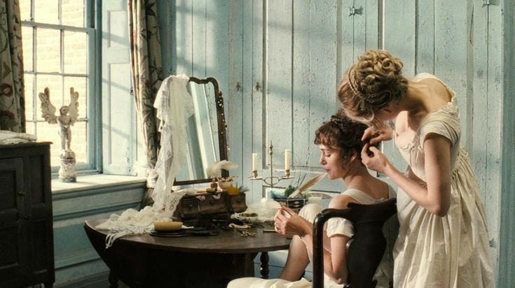 This may contain: two women are sitting in front of a mirror and one is fixing another woman's hair