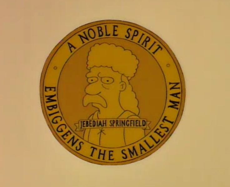 Cartoon roundel of Jebediah Springfield, with the motto: A NOBLE SPIRIT EMBIGGENS THE SMALLEST MAN