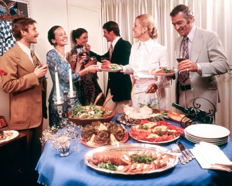 six people gathered round a table laden with food six people gathered round a table laden with food