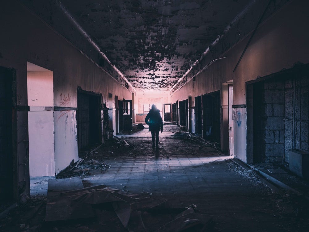 A woman walks down a dark hallway in a rundown building