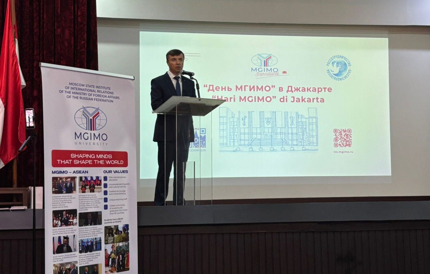 The Russian Ambassador to Indonesia, Sergey Gennadievich Tolchenov, delivered remarks from a podium on a stage with a backdrop written in Russian.