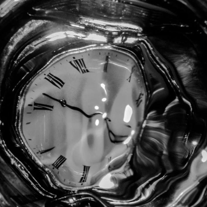 This may contain: a glass vase with a clock in it's center and water around the edges This may contain: a glass vase with a clock in it's center and water around the edges