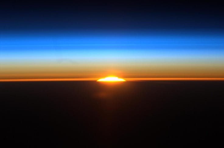This may contain: the sun is setting over the horizon as seen from an airplane in the sky above