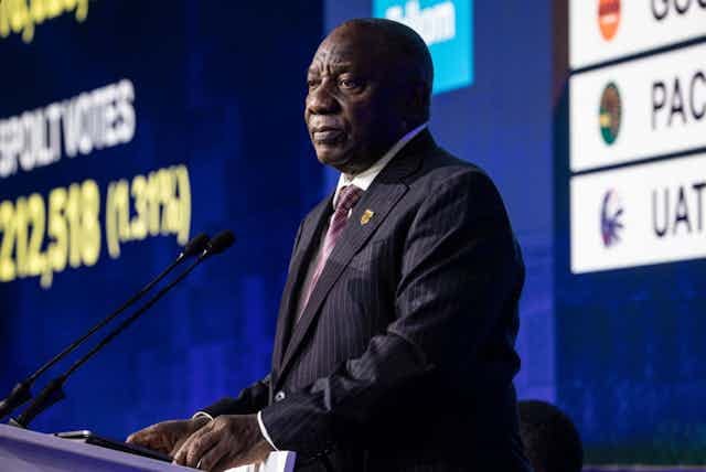 A man in a suit at a podium with microphones A man in a suit at a podium with microphones