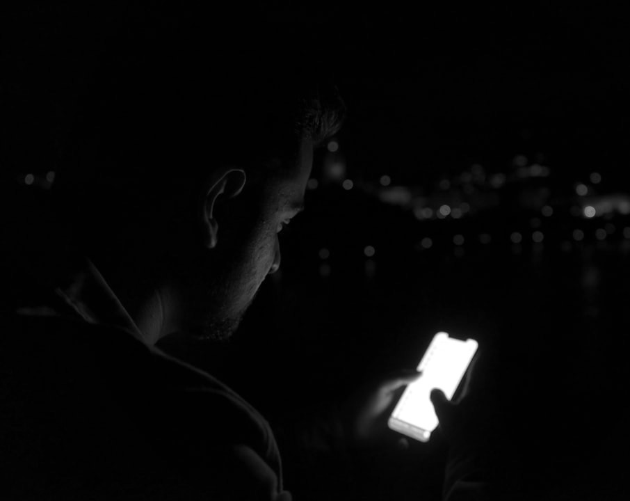 man in black shirt holding white smartphone man in black shirt holding white smartphone