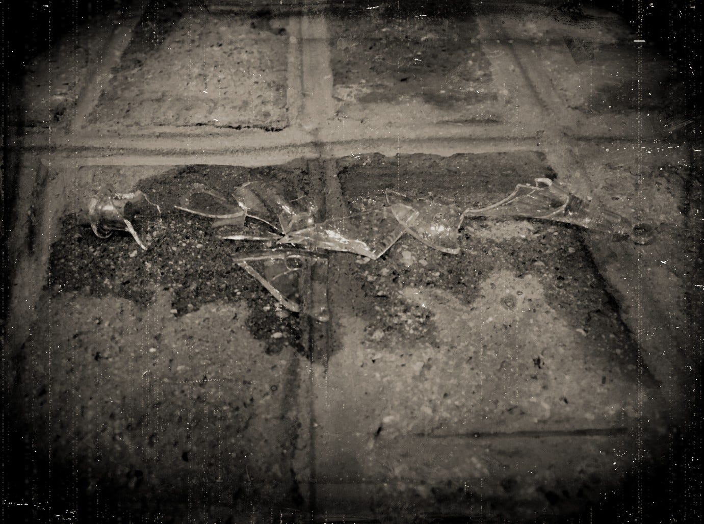 A sepia-toned photo made to look like a Victorian era daguerreotype. The photo shows a broken vial scattered across a brick floor.