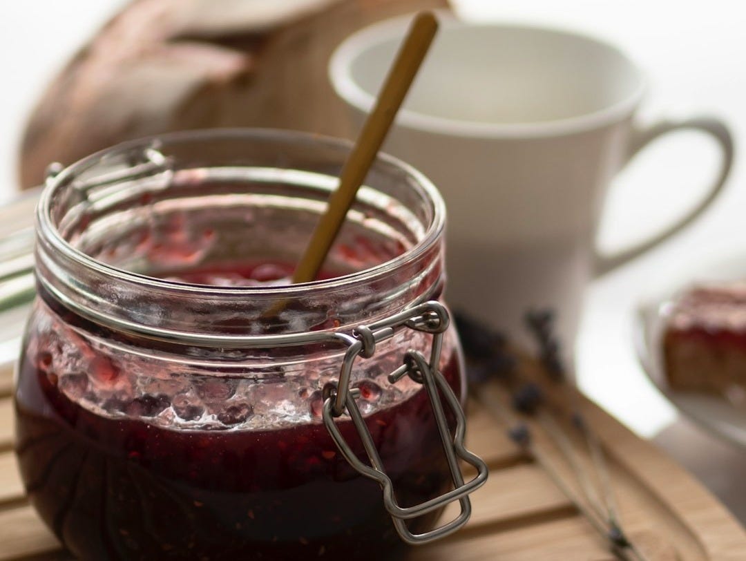 a jar of jam sitting on top of a wooden cutting board