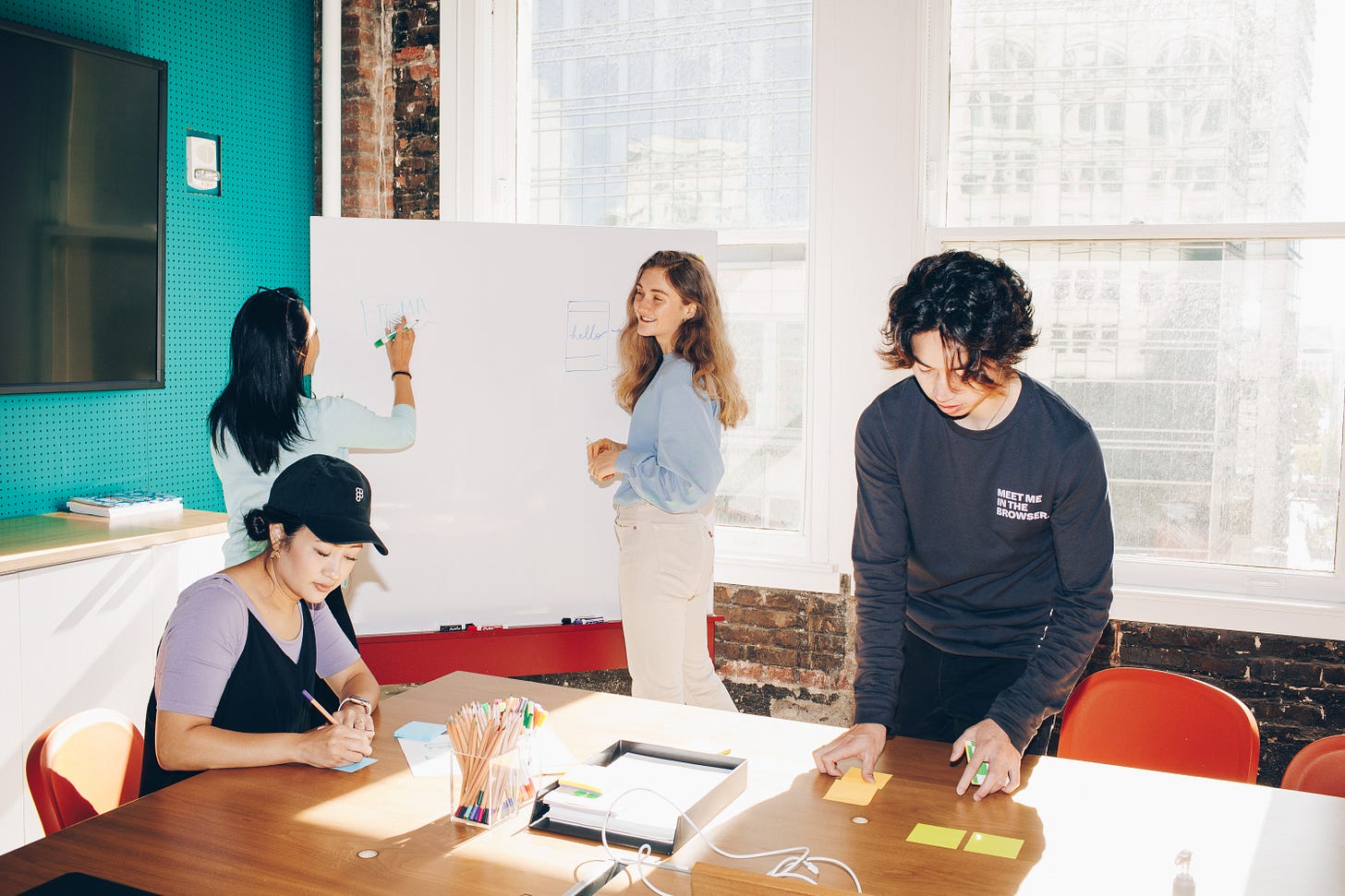 Four people working at a whiteboard and table