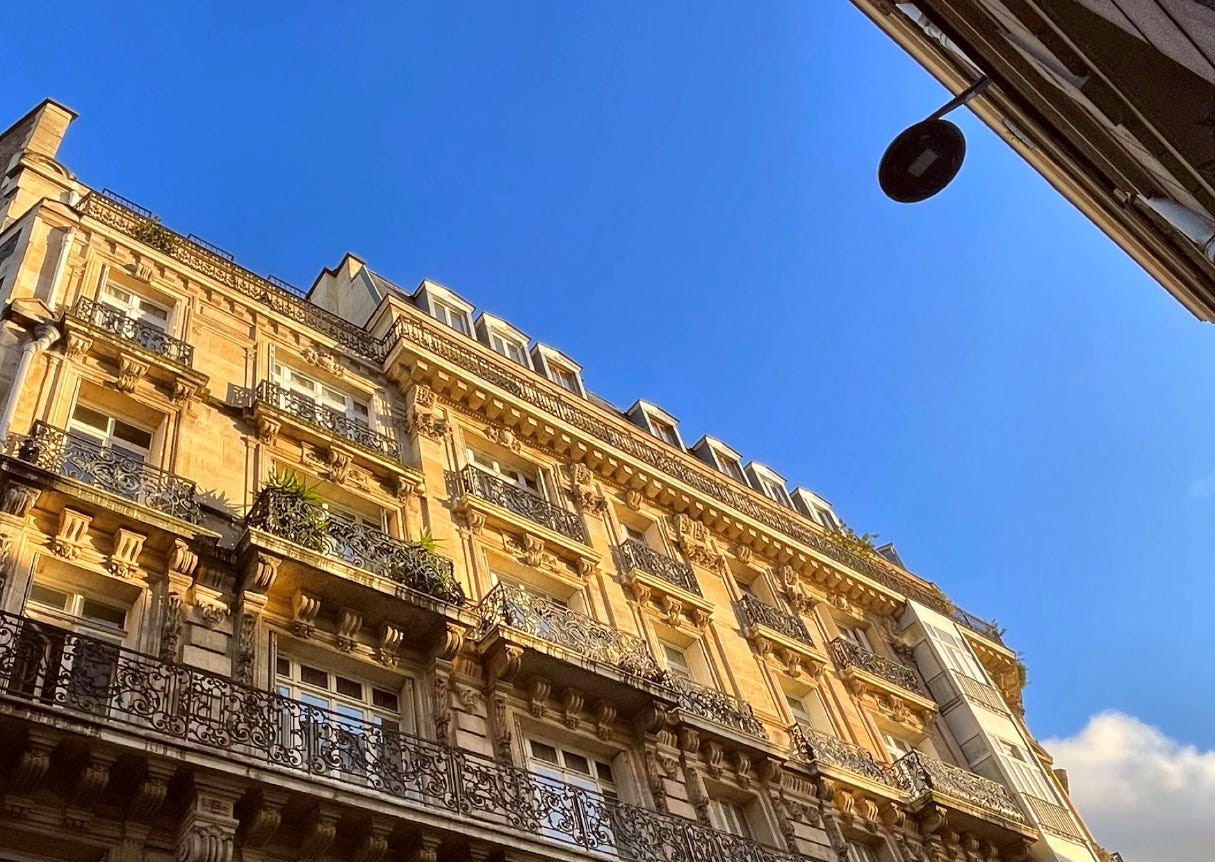 looking up to the blue sky, a typical Parisian apartment block on the foreground looking up to the blue sky, a typical Parisian apartment block on the foreground