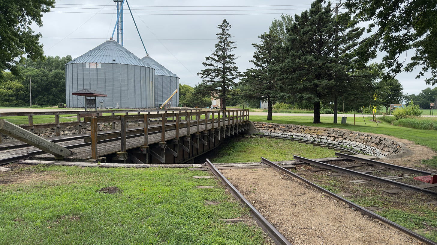 The turntable used to turn trains around at this stop. A bridge with railroad tracks swings from the center point of a large circular hole. Tracks radiate out based on which way the train needs to go.