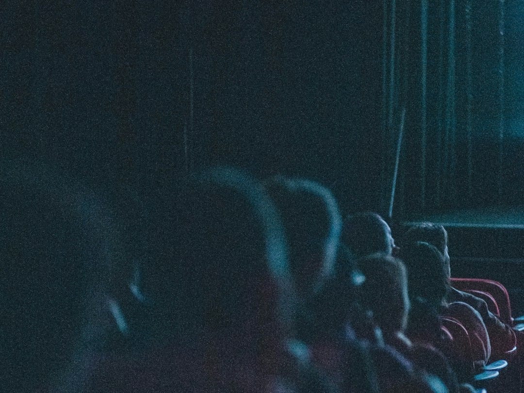 a group of people sitting in a dark auditorium a group of people sitting in a dark auditorium