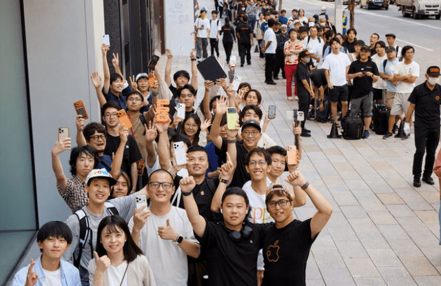 Excited customers, some holding up their new iPhone 17 Pro, line up outside Apple Ginza.