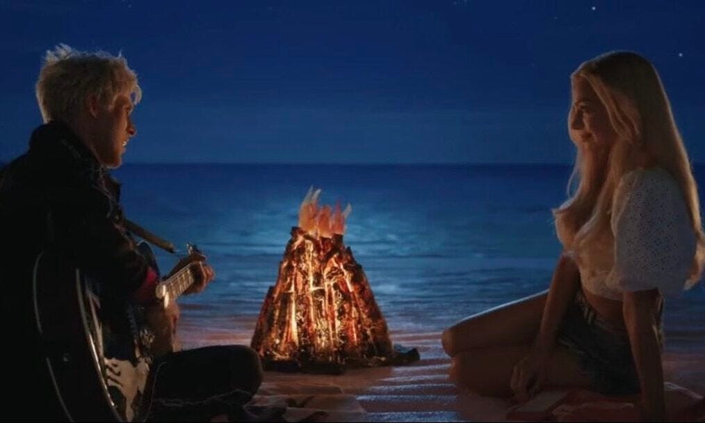 Still from Barbie movie where Ryan Gosling as Ken plays his guitar for Margot Robbie as Barbie over a campfire