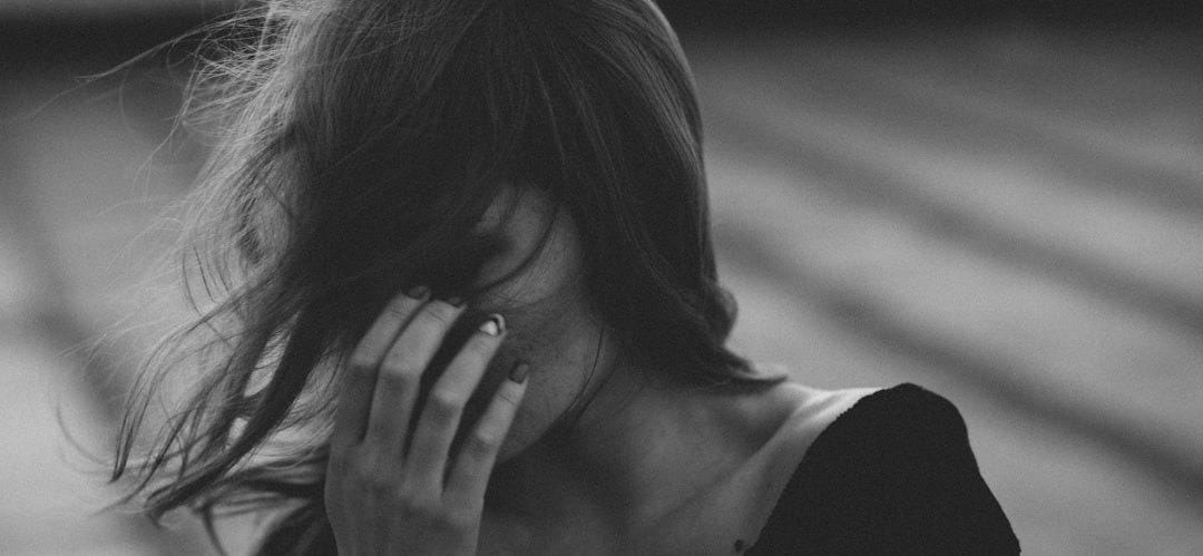 woman in black scoop neck shirt covering her face with her hand woman in black scoop neck shirt covering her face with her hand