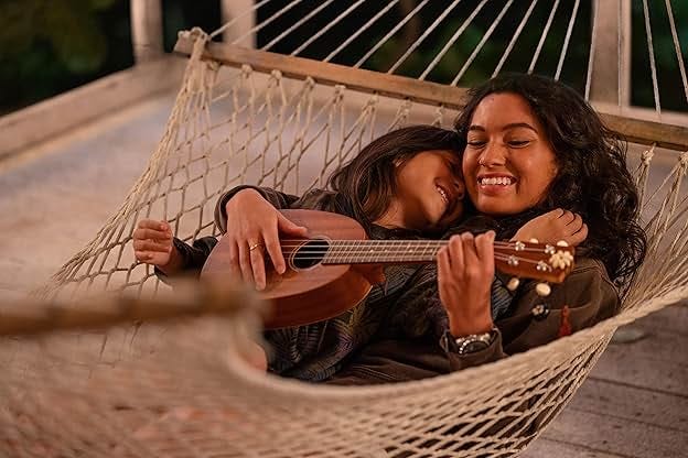 Sisters Lilo and Nani playing a guitar in a hammock smiling. Sisters Lilo and Nani playing a guitar in a hammock smiling.