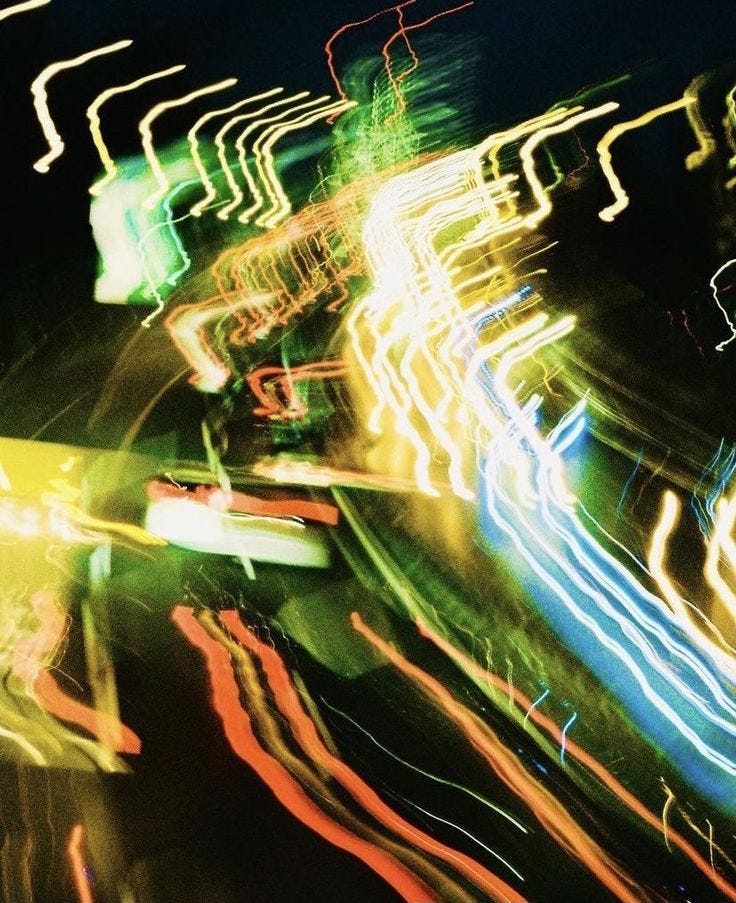 This may contain: blurry photograph of street lights in the night with long exposure and color to enhance it