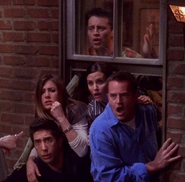 This may contain: a group of people standing next to each other in front of a brick wall and window