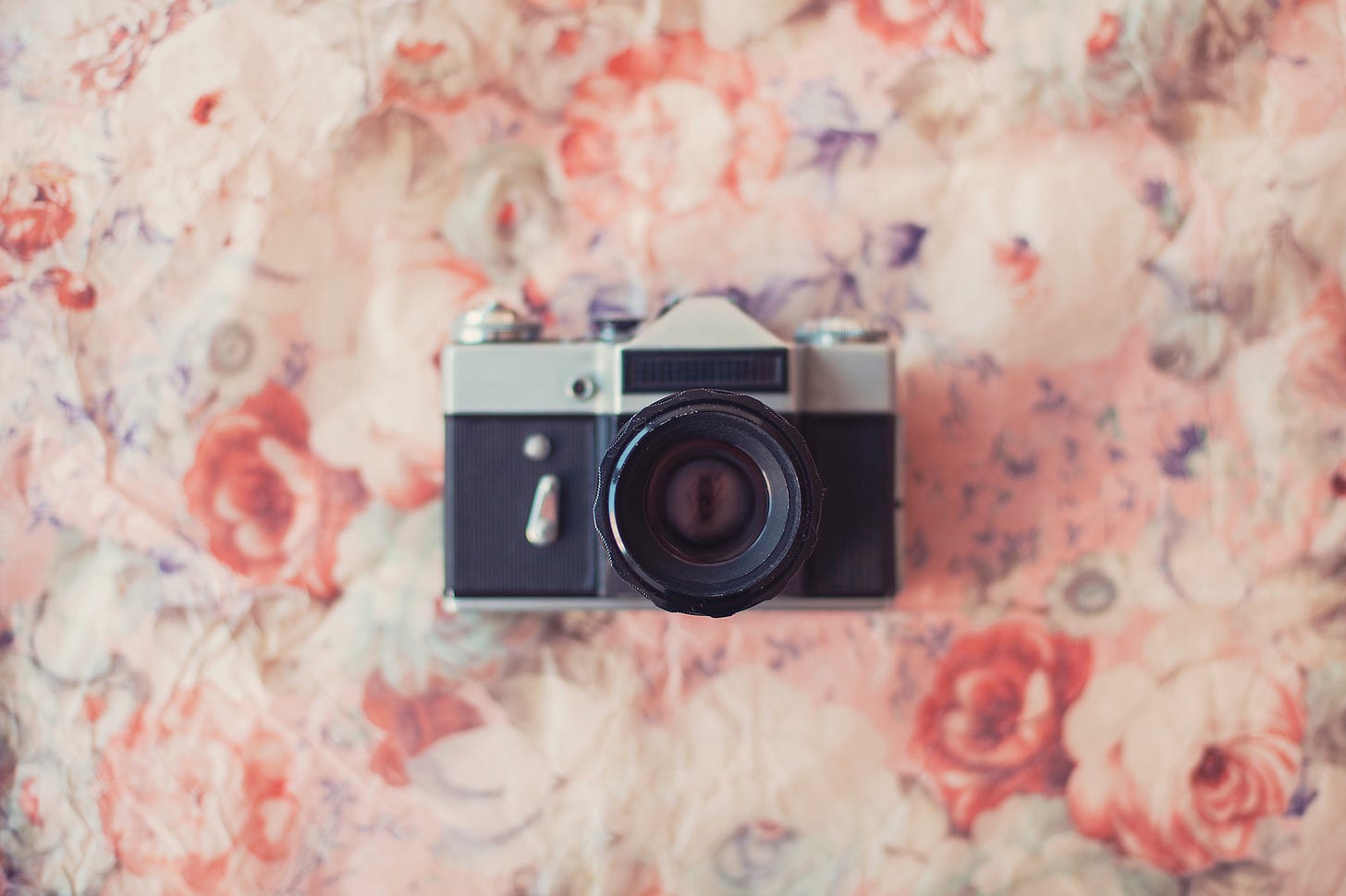 A vintage camera lying on dusty pink floral fabric