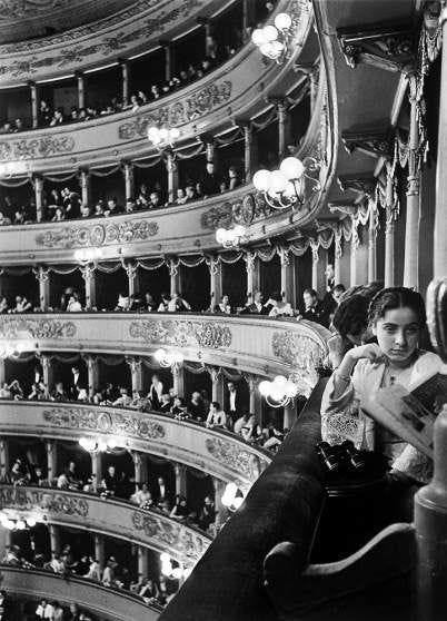 This may contain: an old black and white photo of a woman sitting on the balcony of a theater