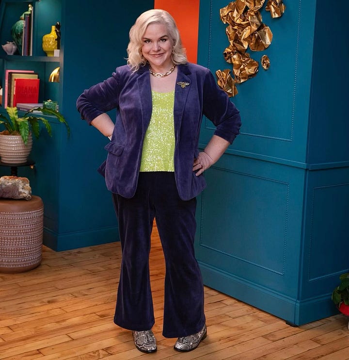 Busy, Caissie and Bette Midler are posing on the set of Busy This Week. Busy is wearing a pleated olive green evening gown. Caissie is wearing a navy velour suit with a lime green shell under the jacket. Bette is wearing a Pucci top in white, blue, black and yellow with white pants. In one photo, they sit smiling. In one photo Busy is posing playfully with her back to the camera. In another, Caissie poses alone to show off her suit. In the final photo, the trio are at the murphy bar on set and they are sharing a huge laugh.