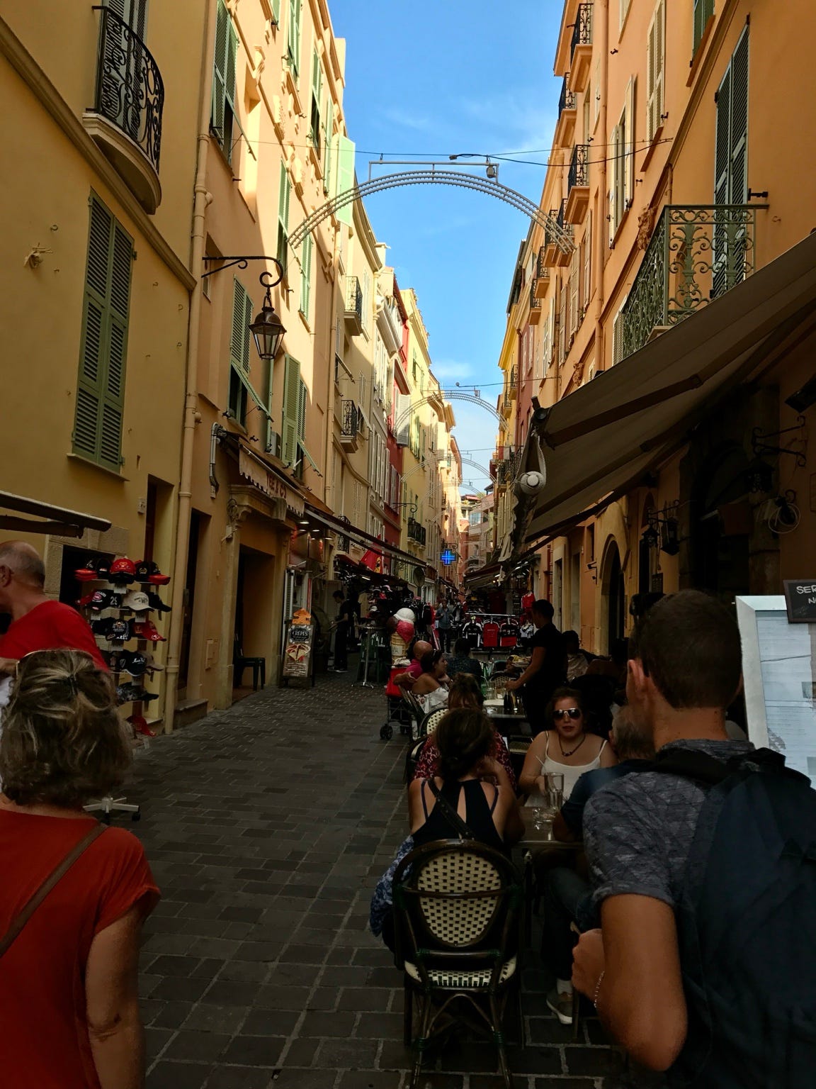 A narrow vernacular street in Monte Carlo, where closely spaced buildings shade and shelter pedestrians, creating an intimate, protected walking environment.