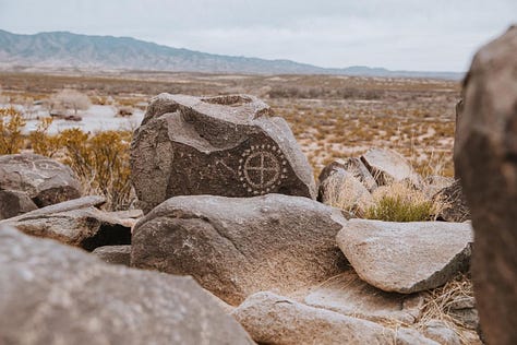 Whitesands National Park, an old saloon/opera house, pink architecture, cowboys eating pie in a cafe, Petroglyph on a boulder