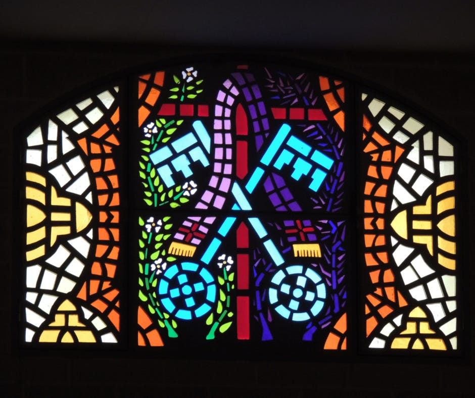 A stained glass window depicting two blue keys crossed amid radiant geometric patterns.