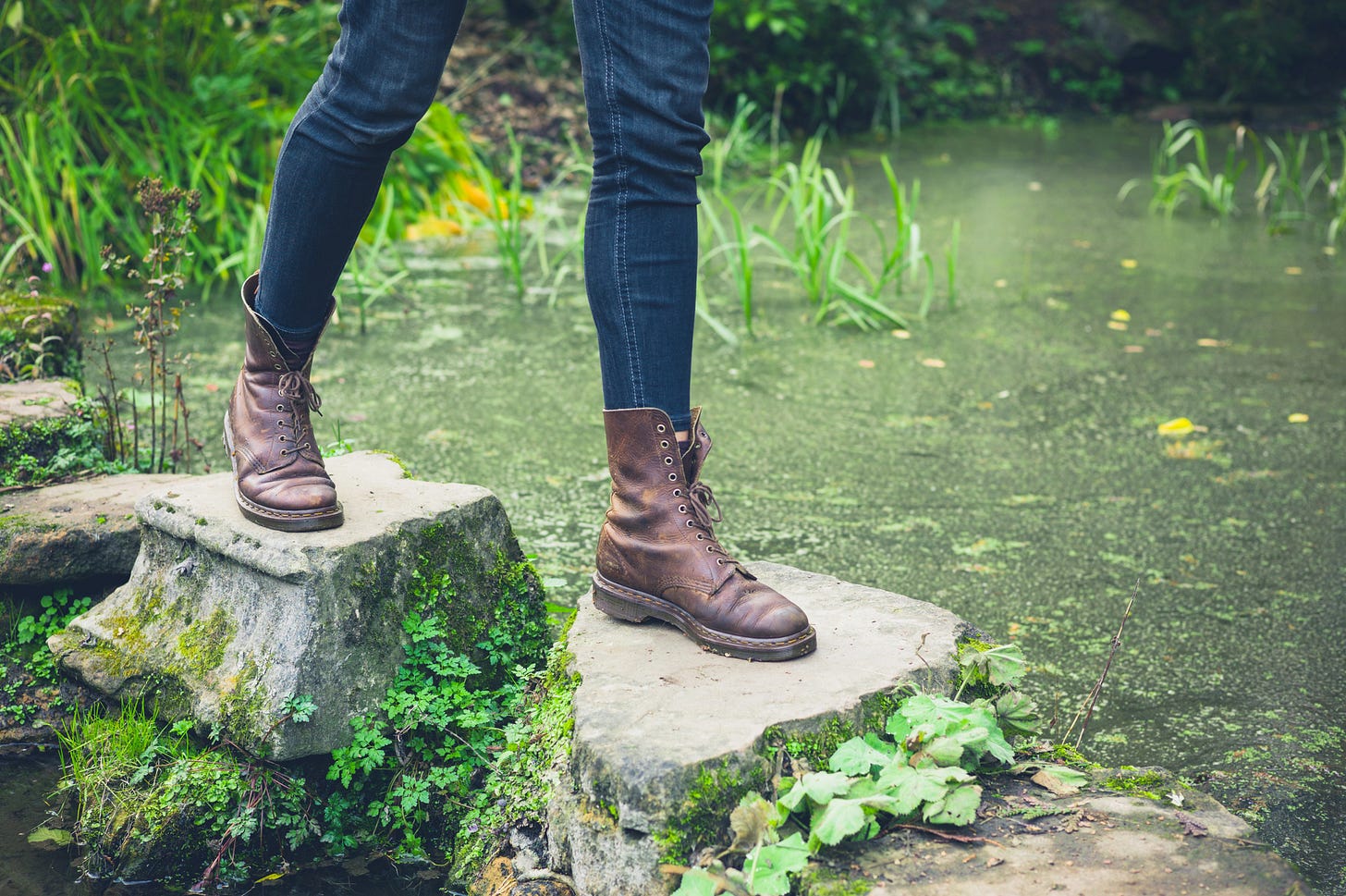 Booted feet walking on stepping stones