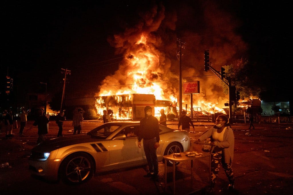 An AutoZone store burns as protesters gather outside on May 28, 2020.