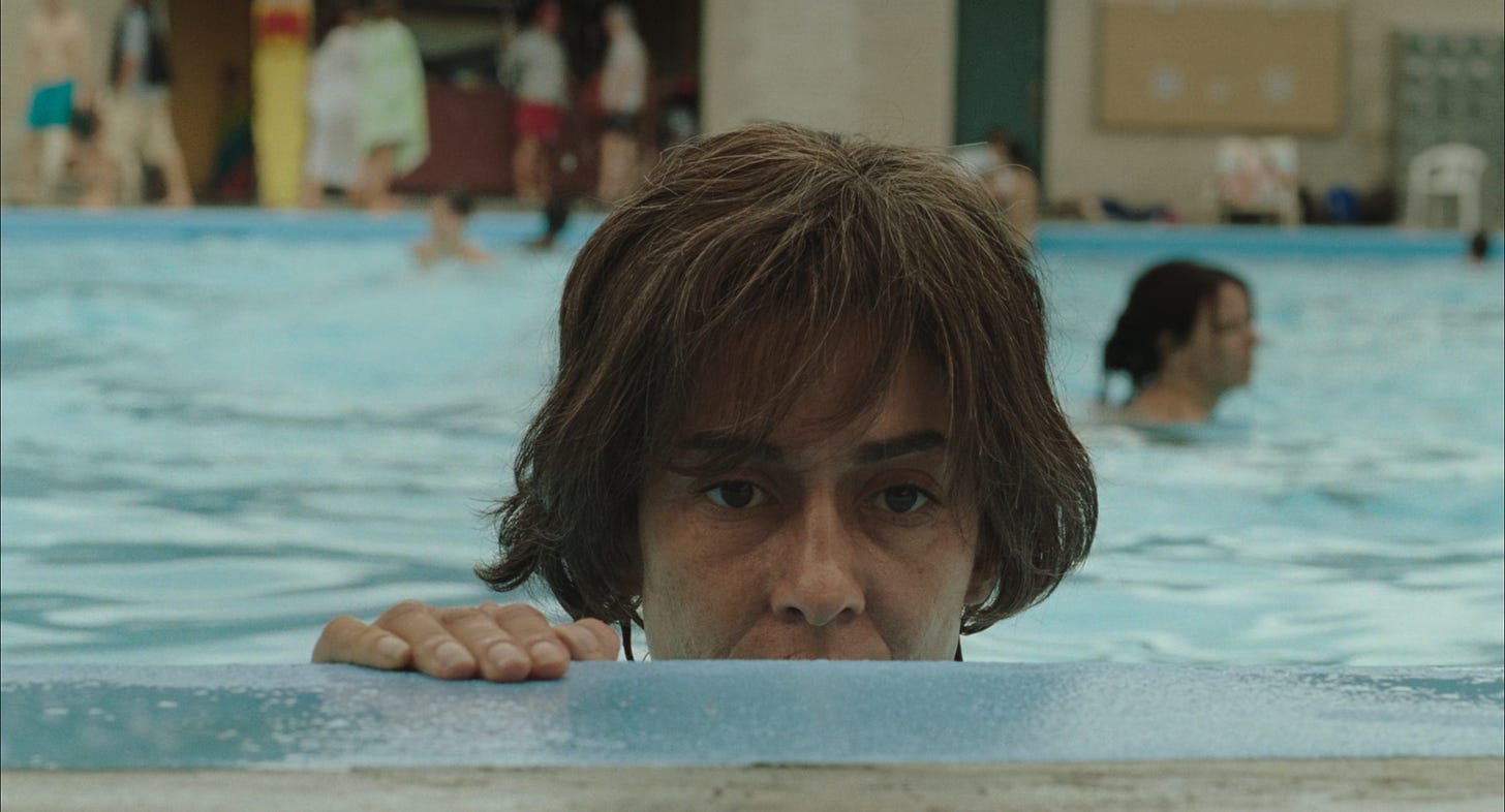A woman peeks from the side of a swimming pool