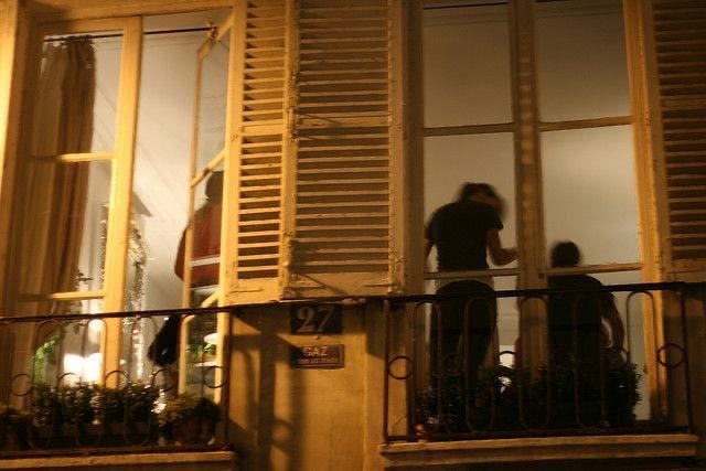 This may contain: two people standing on a balcony at night