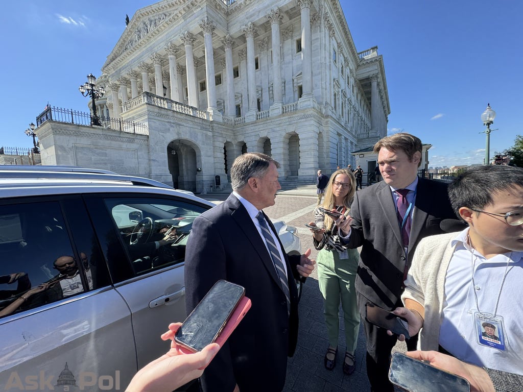 A politician in a suit takes questions from reporters before getting in his staffer's waiting car. Photo Matt Laslo © www.askapol.com