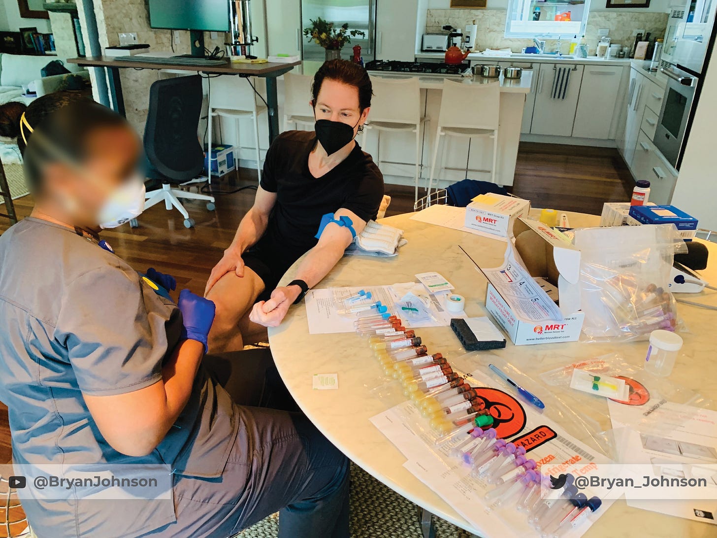 Bryan Johnson undergoing a blood draw at home; rows of labeled vials and test kits on the table