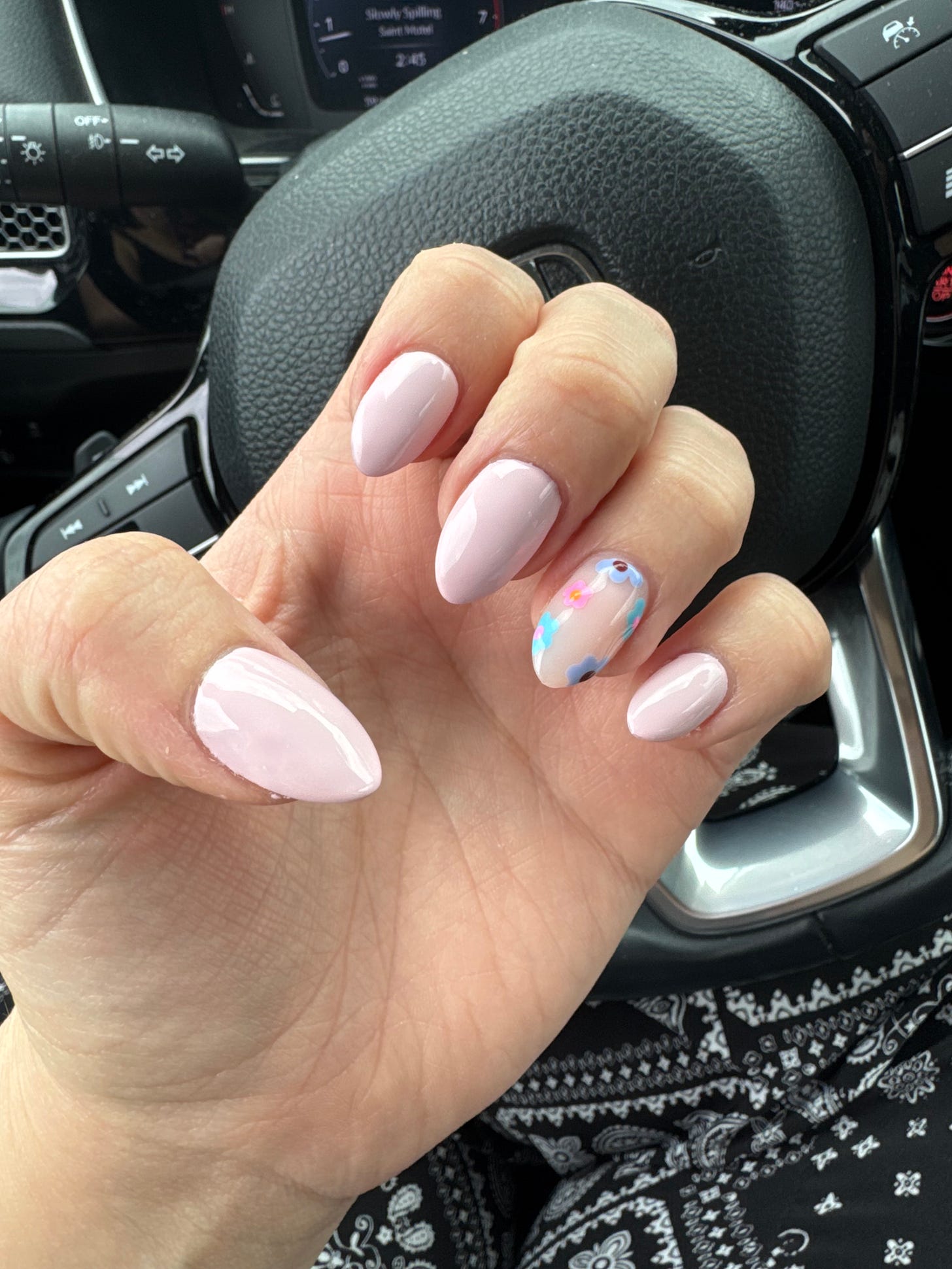 pink almond-shaped nails with a floral design on the ring finger.