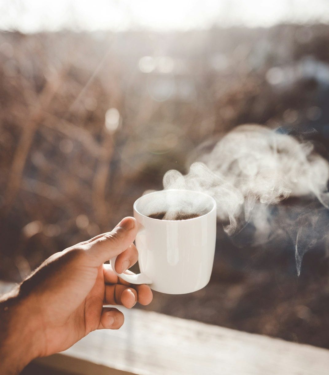 person holding white ceramic cup with hot coffee person holding white ceramic cup with hot coffee