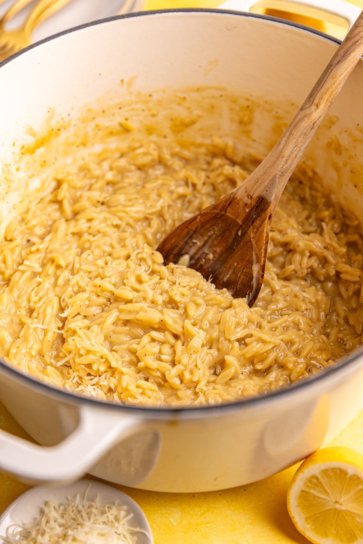 A pot of freshly cooked Creamy Lemon Orzo, with a wooden spoon.