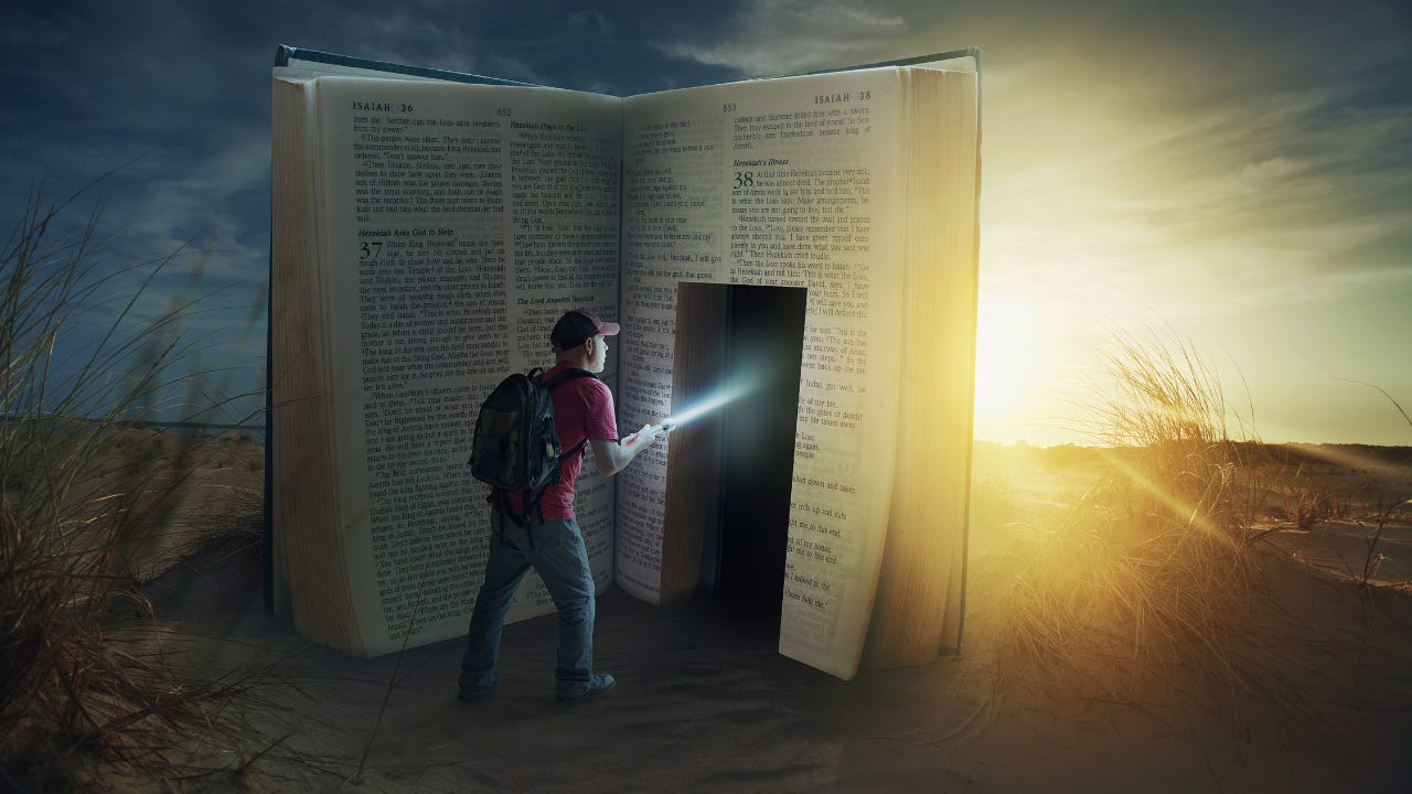 A man with a flashlight about to walk into a large copy of the Bible. A man with a flashlight about to walk into a large copy of the Bible.