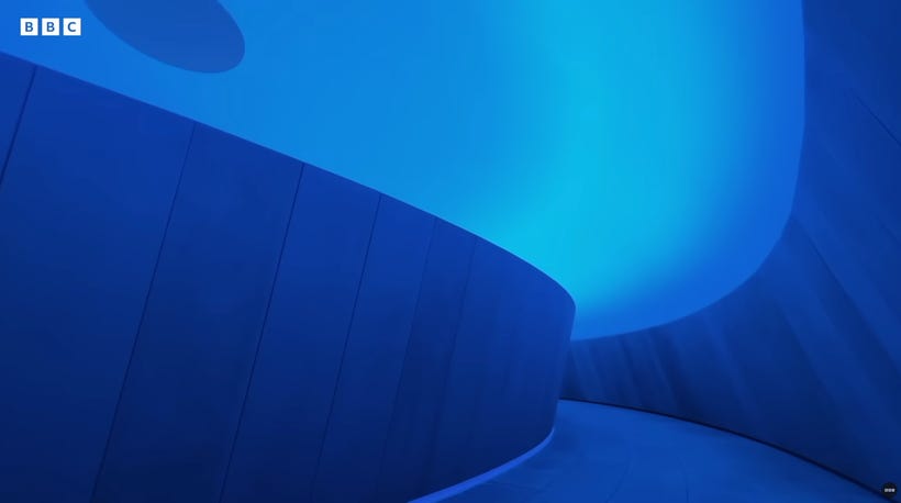 Blue light fills the entirety of a curved hallway, from floor to ceiling