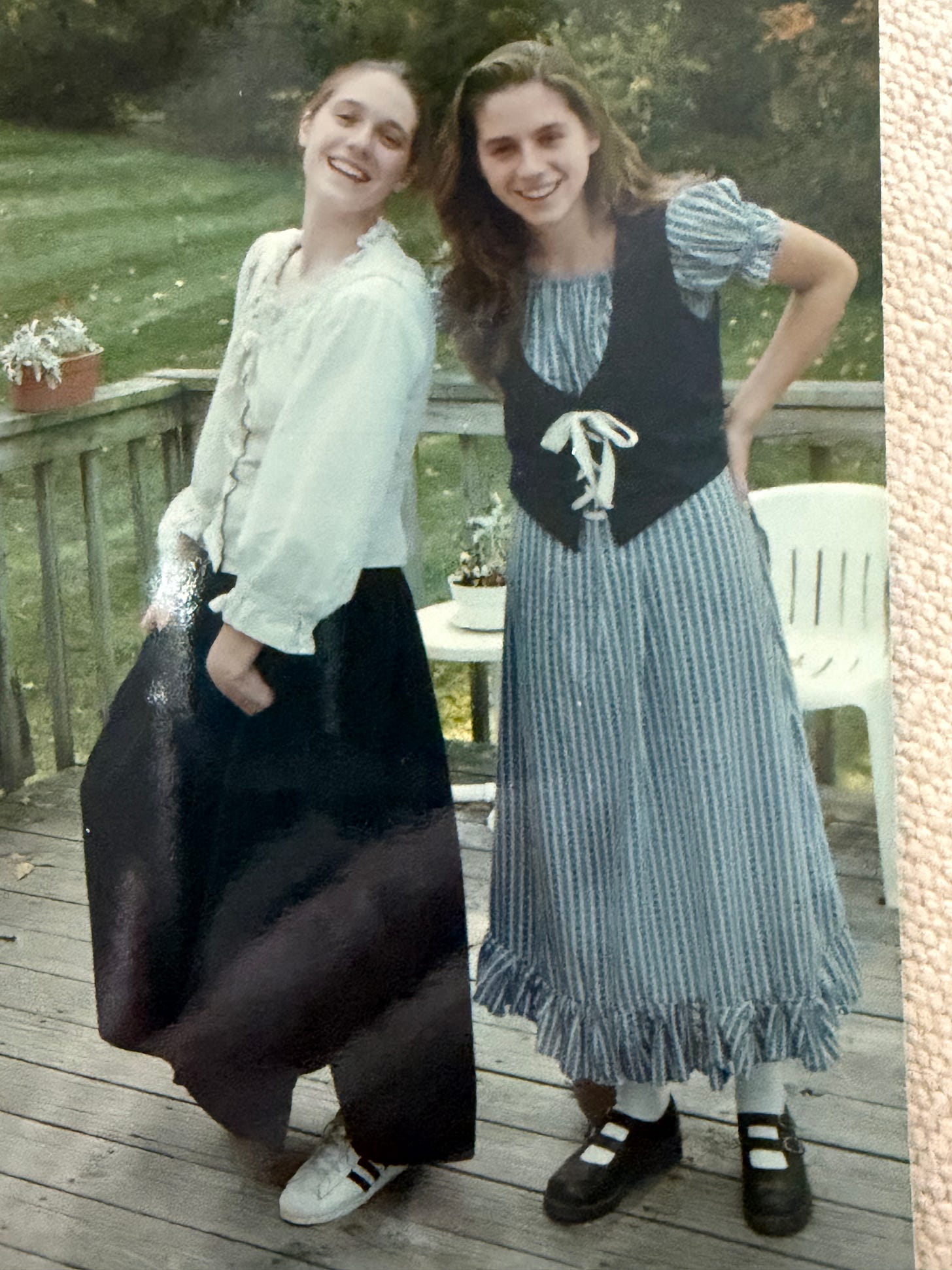 Photo from the 1990s of two young women wearing colonial costumes standing on a deck.