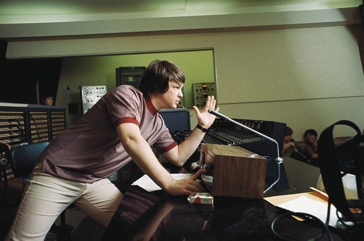 This may contain: a young man holding a microphone in front of a recording equipment set up on a desk
